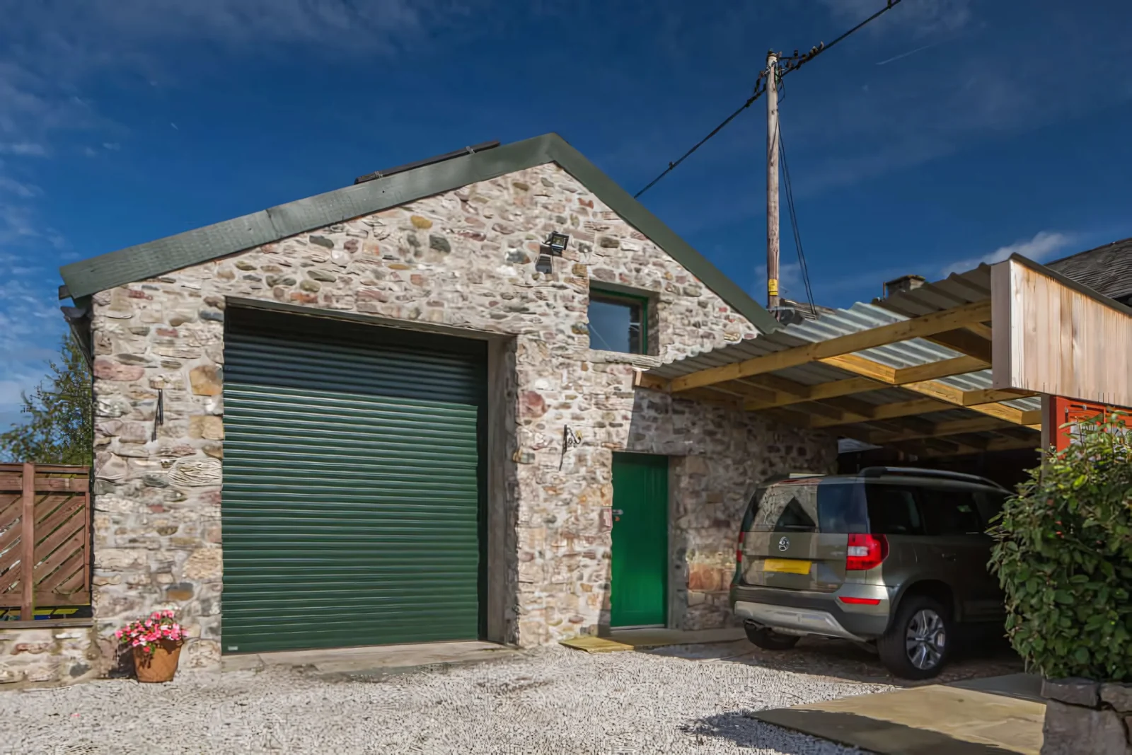 Green roller garage door on a traditional stone garage